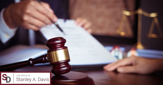 Gavel resting on a lawyer's desk with a client's hand in the background